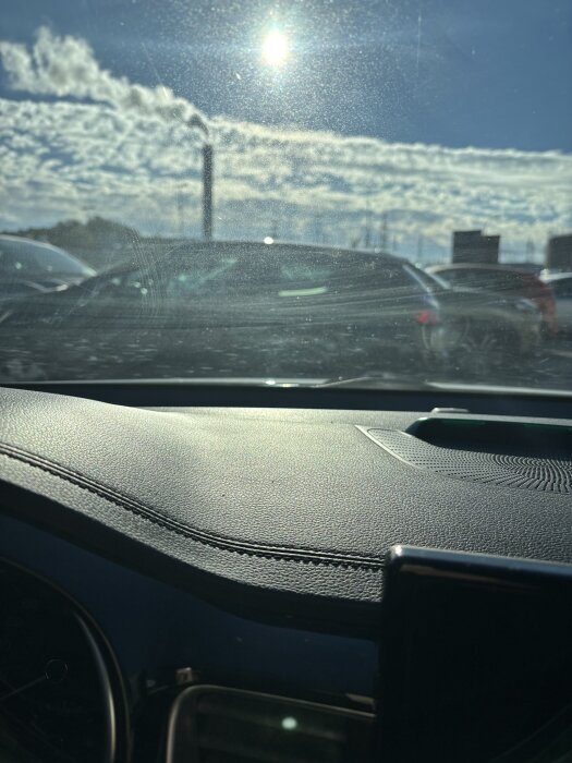 Bilruta i solljus med hinna och små prickar synliga.