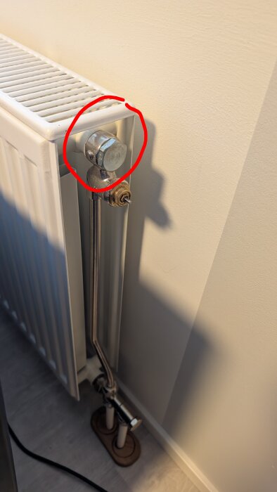 Inringad skruvdel vid sidan av en radiator som inte fungerar; problem med vattencirkulation och värmespridning.