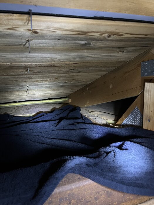 Träpanel i tak med handduk för att övervaka eventuell fukt. Taket är 35 år gammalt, bilden visar ingen synlig fukt vid tidpunkten för fotot.