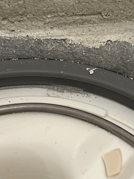 Spricka eller fog i betongvägg med närbild på tätning och avslitet material.