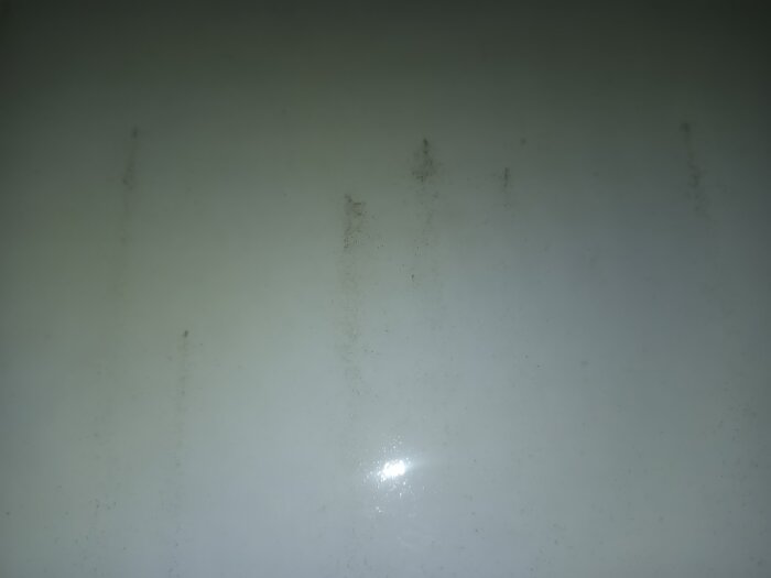 Ytan med mörka prickar och smutsfläckar under mörka förhållanden. Lacken är slät men smuts fastnar i de små porerna.