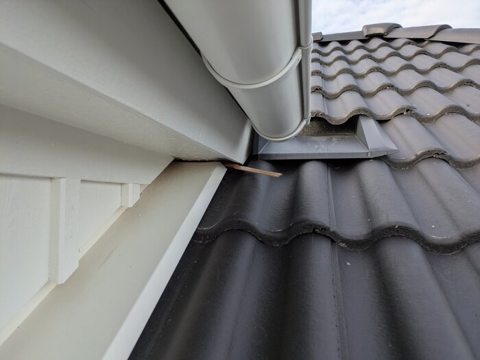 Takkupa med felaktigt tätat innerhörn, synlig tumstock under takpannor vid hängränna och plåt, problem med vattenläckage vid regn.