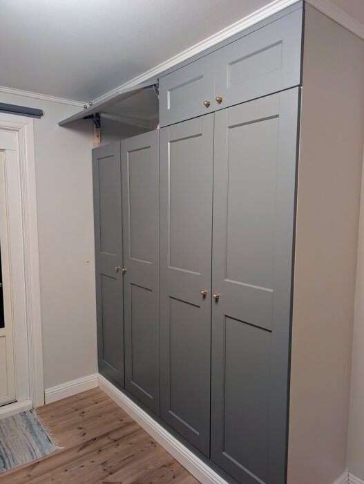 Gråa överskåp gjorda av MDF ovanpå PAX-garderober, med mässingsknoppar och vita taklister; en del av hembygge projekt.