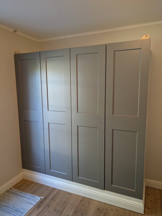 Gråa PAX-garderober modifierade med hemmabyggda överskåp i mdf, målade i samma färg, med vit tak- och golvlist runt om.