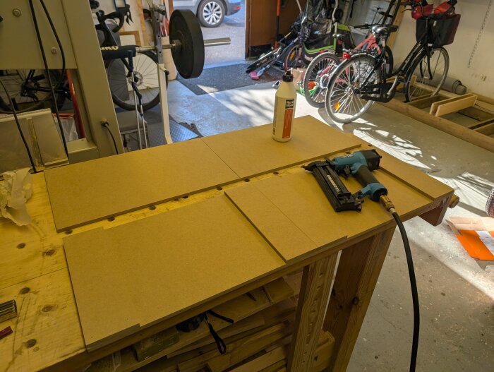 MDF-skivor och dyckertpistol på arbetsbänk i verkstad, redo för att bygga anpassade överskåpsluckor till PAX-garderob.