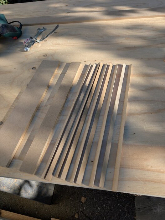 Trekantslister i MDF och verktyg på ett träbord, del av gör-det-själv-projekt för att tillverka överskåp till PAX-garderob.