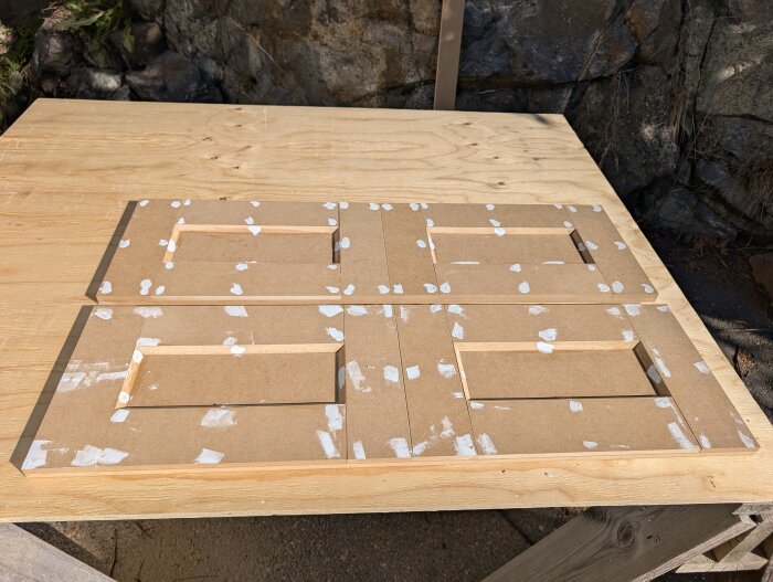 MDF-skivor med urtag och spacklade skruvhål på arbetsbänk; förberedda för att bli luckor till byggprojekt.