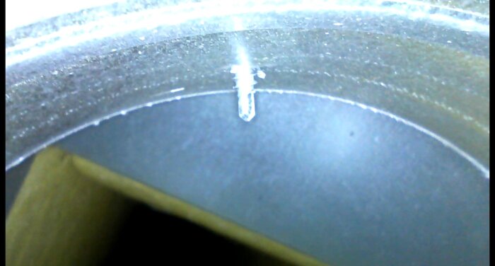 Närbild på ett ventilationsrör med en inbuktning och en skruv, troligen en del av ventilationssystemet.