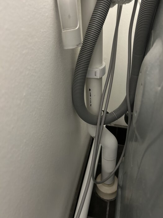 Avloppsrör bakom tvättmaskin visar en slang utan synligt vattenlås där avloppslukt förekommer enligt inlägget.