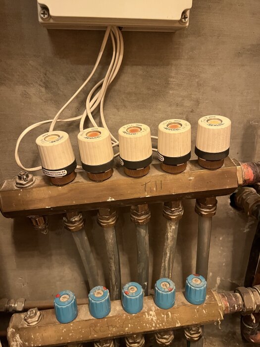 Golvvärmesystem med flera termostater och röranslutningar i metall, del av en hemmainstallation, diskuterande funktionalitet och felsökning.