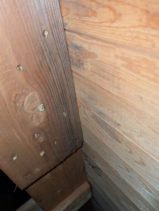 Svart missfärgning på trätakbjälkar nära skorstenen på vinden, synlig i närbild.