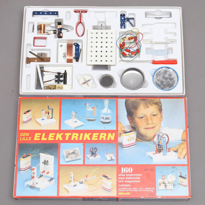 Experimentlåda 'Den lille elektrikern' med komponenter och instruktioner för elektriska experiment. Förpackning med bild på barn och experiment.