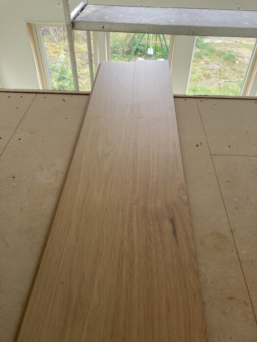 Nytt Bjelins golv lagt ovanpå underlag i ett rum med utsikt över en grön trädgård genom stora fönster.