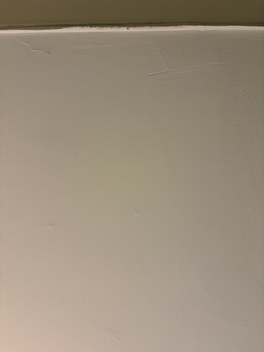 Ojämn och fläckig yta på målad vägg med synliga skarvar och ojämnheter i hörn, resultat av bristande förarbete och målning.