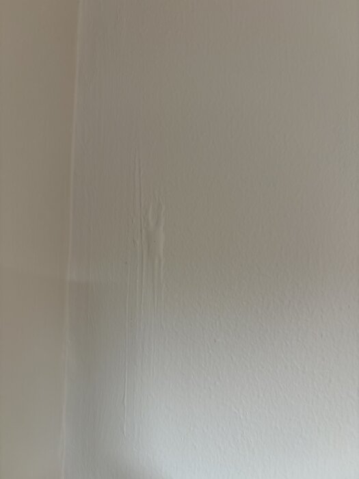 Ojämn målad vägg med tydliga spår av bristfälligt spacklingsarbete, där underlaget inte har jämnats ut före målning.