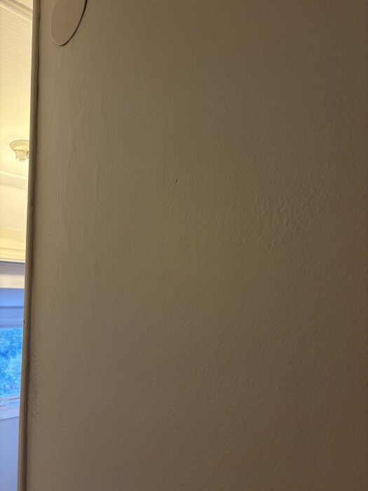 En vägg med ojämnt målad yta och skiftningar, uppstått på grund av bristfälligt förarbete och slipning.