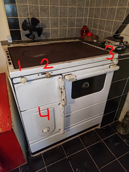 Gammal vedspis med fyra numrerade vred. Nummer 1, 2, 3 och 4 markerade i rött mot en bakgrund av kakel och köksredskap.