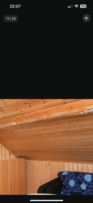 Inuti en stuga med synliga takbjälkar och ett vitt/nött utseende på en av bjälkarna.