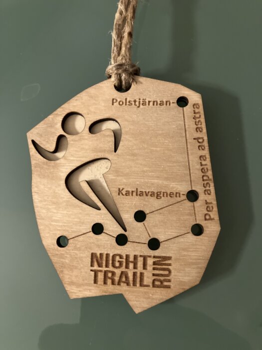 Trämedalj med stjärnkonstellationen Karlavagnen och texten "Night Trail Run" samt "Polstjärnan" och "Per aspera ad astra".