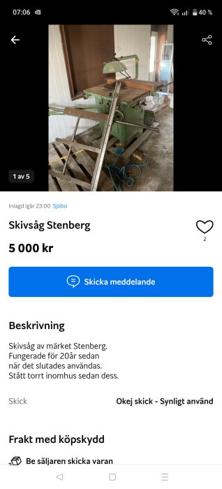 Grön skivsåg av märket Stenberg står i ett rum. Den är monterad på en träpall och omgiven av verktyg och material.