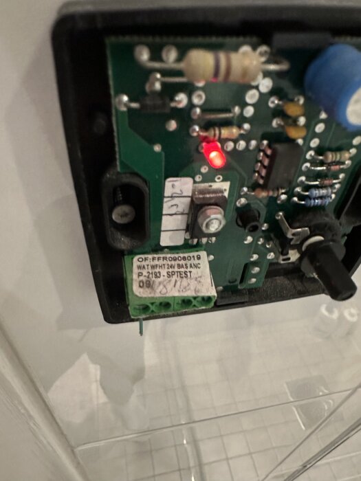Närbild av inre komponenterna på en golvvärmetermostat med en röd lysdiod och märkt "WAT WFHT 24V BAS ANC P-2193".