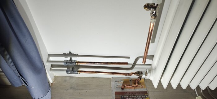 Kopparrör och ventiler vid en vägg, slutfix vid radiatorinstallation.