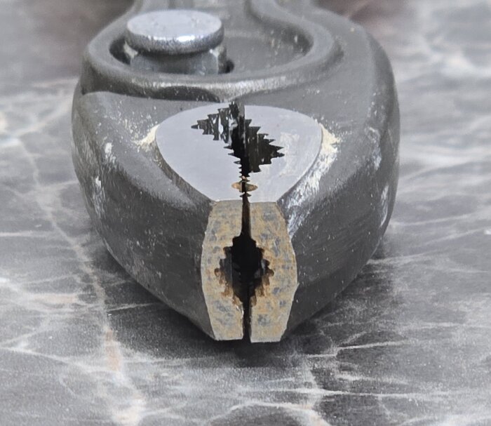 Närbild av en tång med ojämn öppning, på ett marmorerat underlag.