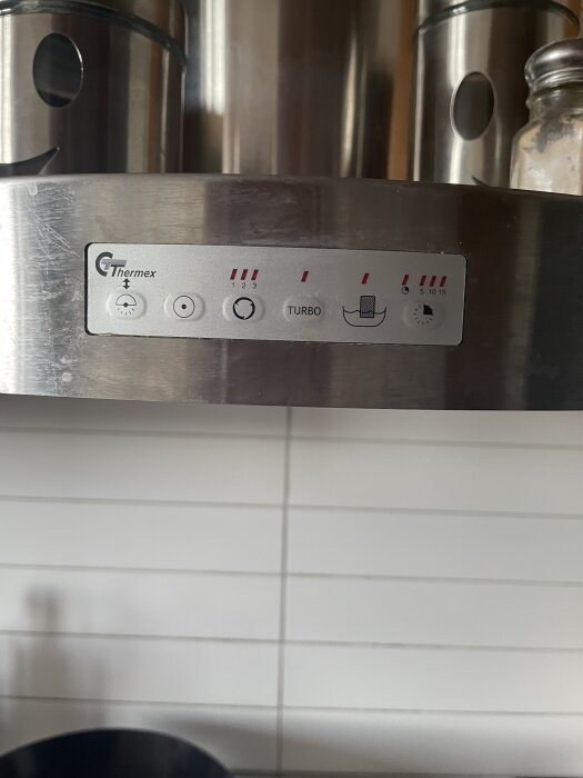 En närbild av kontrollpanelen på en köksfläkt från märket Thermex med olika ikoner och inställningar.
