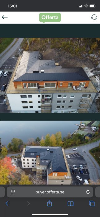 Luftbild av flerbostadshus med svart tak och träfasad, omgiven av natur och parkeringsplatser i Södertälje.