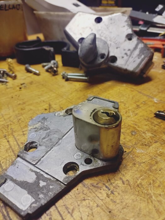 Garageportens trasiga låsdetaljer på en arbetsbänk med verktyg i bakgrunden.