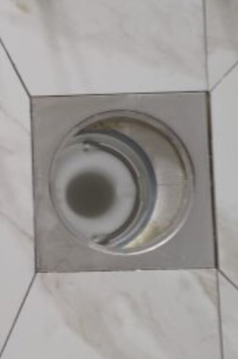 Golvklinkers och metallram med ojämn glipa runt duschbrunn.