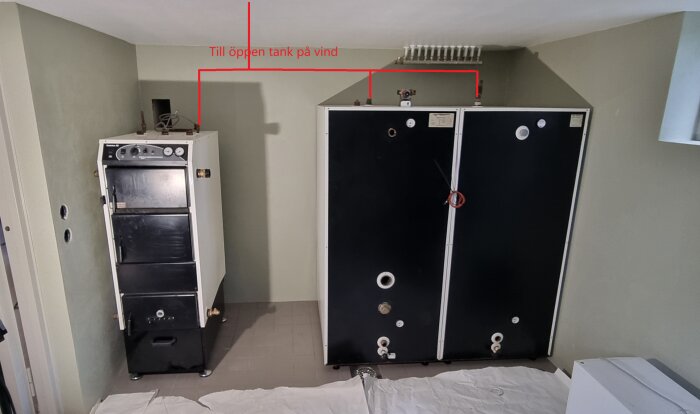 Vedpanna och tankar i ett pannrum med röda markeringar som visar kopplingsförslag för expansionen till öppen tank på vinden.