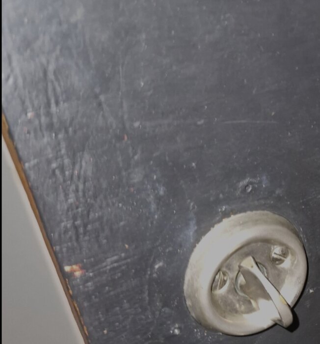 Sliten dörryta med djupa skrapmärken ovanför ett silverfärgat handtag.