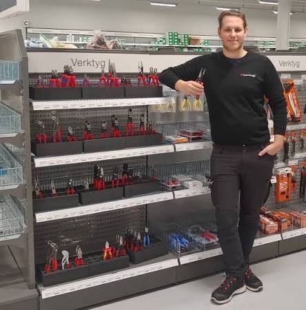 En person står vid en hylla med verktyg i en butik, verktygen inkluderar olika typer av tänger och andra handverktyg.