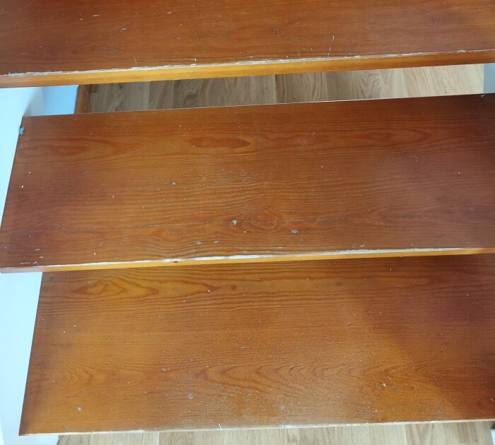 Trätrappsteg med slitage och repor, fundering om att slipa och måla för renovering.