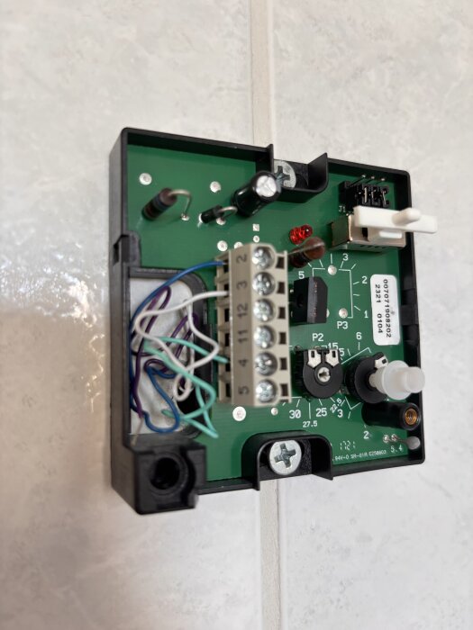 Styrbox för golvvärme med öppnad kapsling, visar kretskort och anslutningsplintar med flera kablar anslutna.