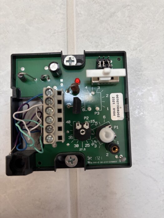 Närbild av en kretskortsenhet för golvvärmesystem med komponenter och anslutningar synliga.