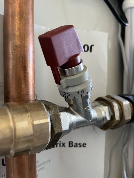 Flödesventil för golvvärme med kopparrör och gradskiva för inställning.