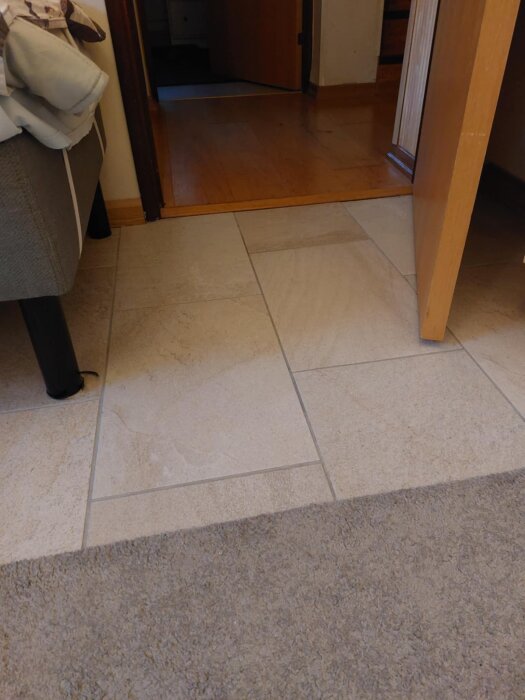 Klinkergolv i källarrum med dörröppning mot ett högre trägolv.