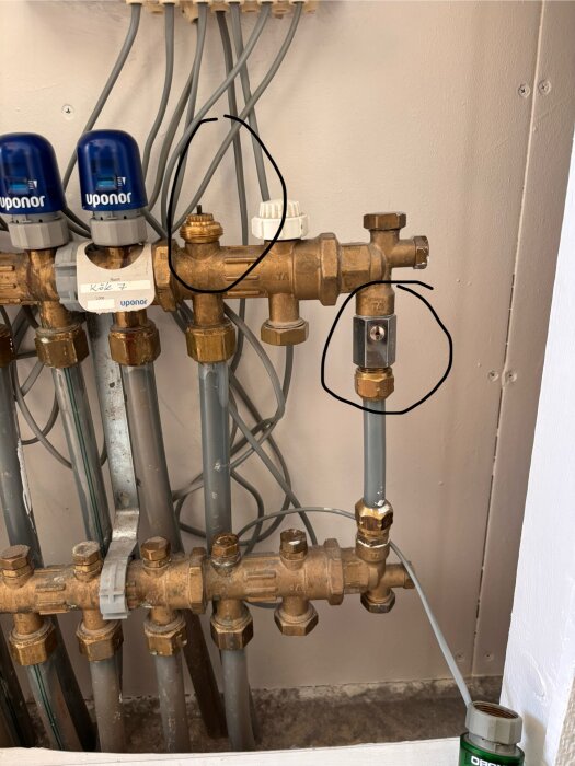 Värmepumpsystem med rörkopplingar och ventiler från Uponor, två delar markerade med svarta cirklar enligt diskussionsfrågan om cirkelpump.