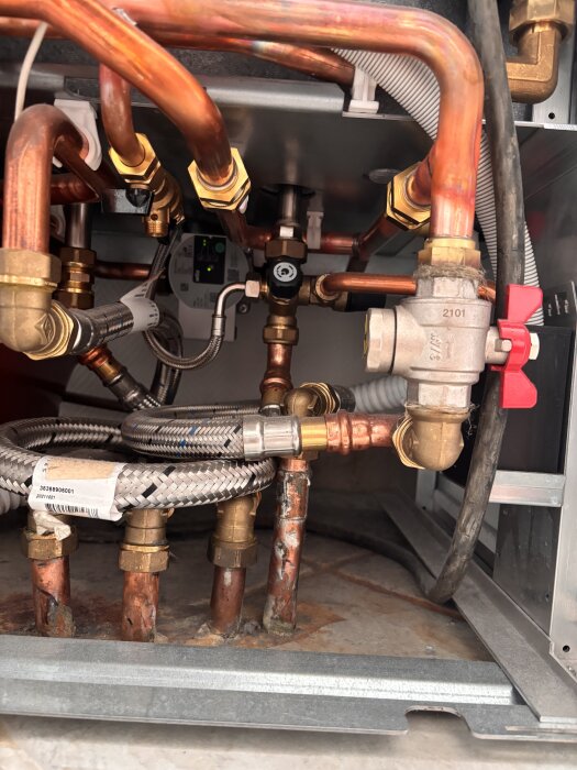 VVS-rör och kopplingar under vask, med avstängningsventil och cirkulationspump markerade för diskussion om bergvärmesystem.