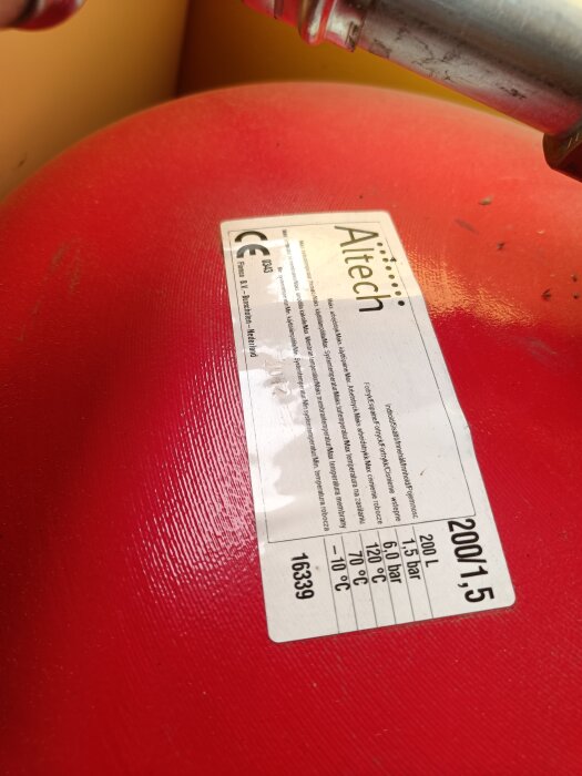 Närbild på en röd expansionstank med en etikett märkt "Altech" och detaljer om tryck och temperatur.