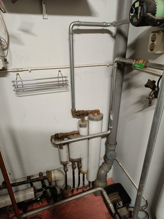 Rörinstallation i pannrum med metallrör och vita ackumulatortankar, en Perfecta aPump, och diverse rörkopplingar vid en vägg.