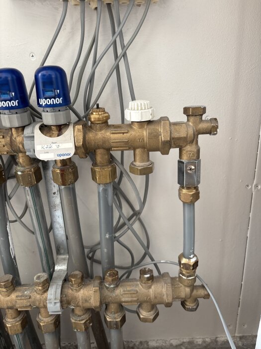 Rörsystem med kopplingar och ventiler från Uponor installerade på vägg.