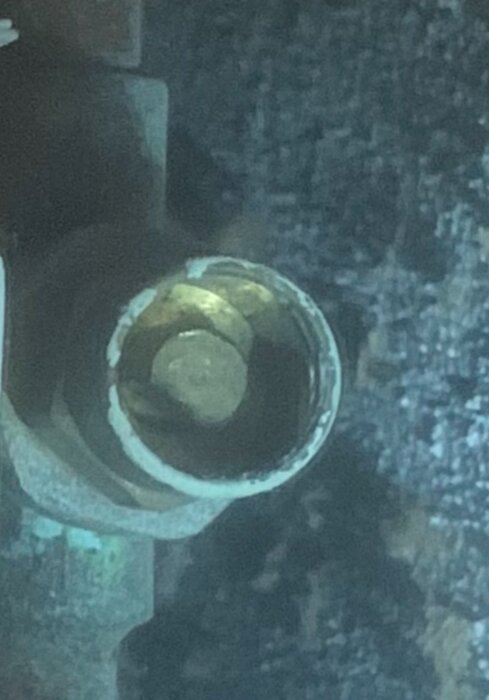 Slutet av ett rör med grönfärgade mineralavlagringar inuti.