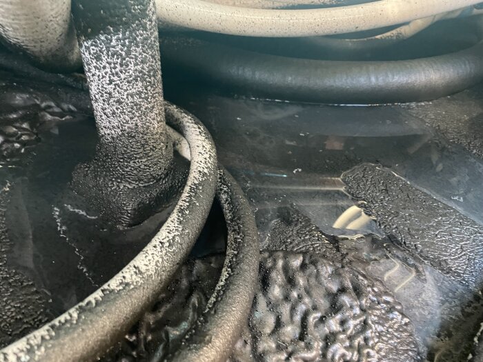 Slangar och fuktig yta under spabad som visar potentiell vattenläcka.