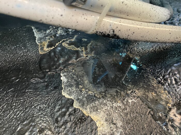 Läckage i spabad med synligt vatten på botten, omgivna av rör och fuktfläckar, vilket indikerar potentiellt läckande sektion.