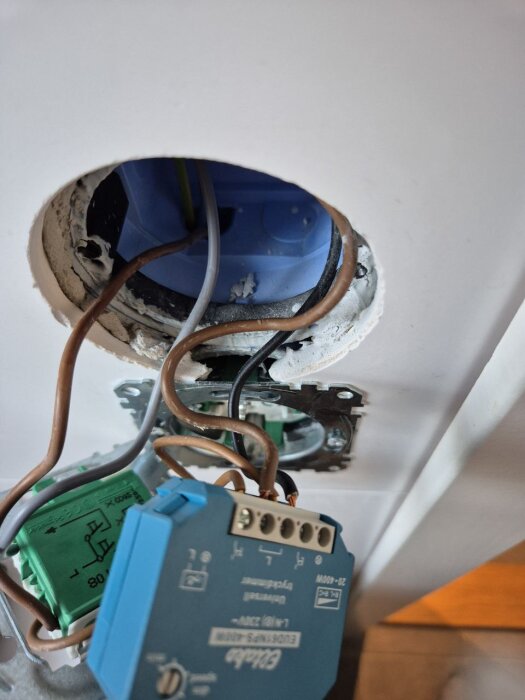 Elektrisk kopplingsdosa med exponerade ledningar och inkopplingsdon i en vägg.