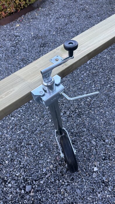 Trähjulställ och metalldel på båtvagn, stående på grus.