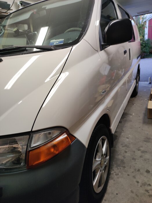 En nyvaxad vit campingbuss parkerad inomhus, redo för vinterförvaring.